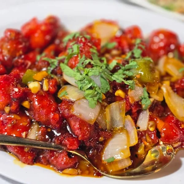 Close-up of Halal Chinese Indo Pak Restaurant's chili chicken with onions, peppers, and cilantro.